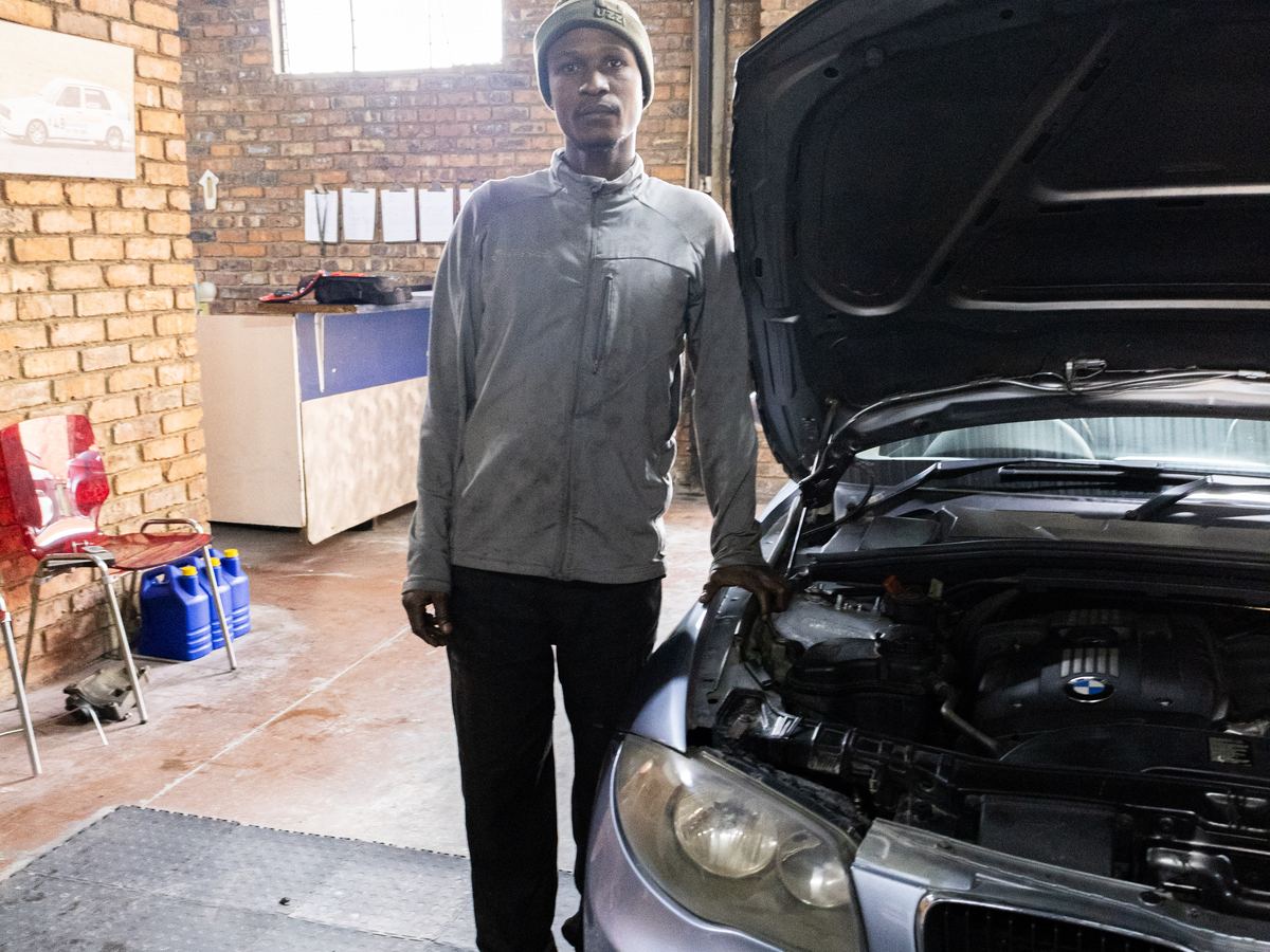A CRS Auto technician standing beside a BMW with its bonnet raised in the Fairland workshop