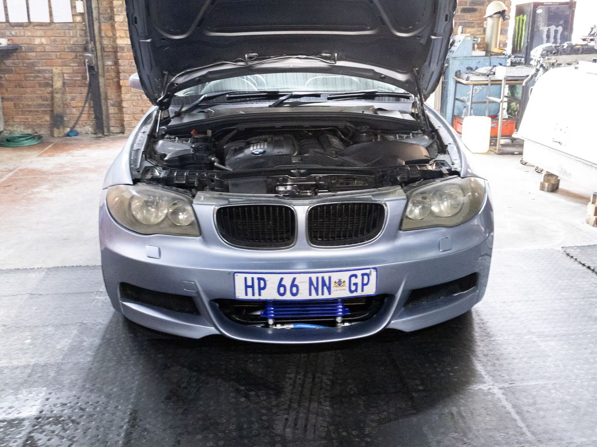 A BMW 1 Series with its bonnet up in the CRS Auto workshop