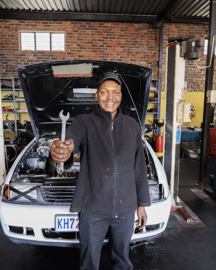 A CRS Auto technician holding a spanner in front of a car